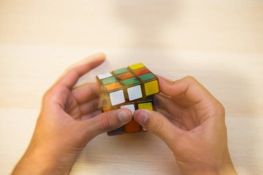 Elleri renkli bir yapboz. Rubik küpü 3 'er 3' er tahta bir masada yatıyor.