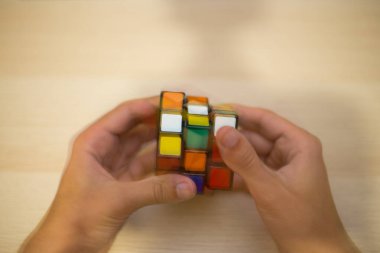Elleri renkli bir yapboz. Rubik küpü 3 'er 3' er tahta bir masada yatıyor.
