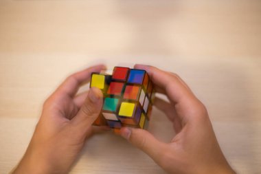 Elleri renkli bir yapboz. Rubik küpü 3 'er 3' er tahta bir masada yatıyor.