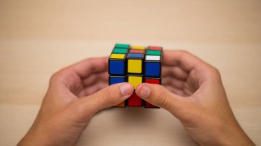 Elleri renkli bir yapboz. Rubik küpü 3 'er 3' er tahta bir masada yatıyor.