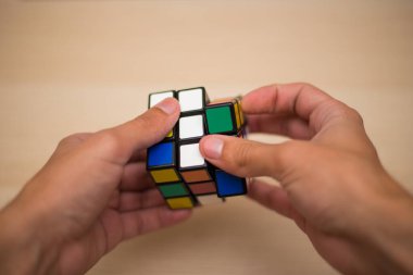 Elleri renkli bir yapboz. Rubik küpü 3 'er 3' er tahta bir masada yatıyor.