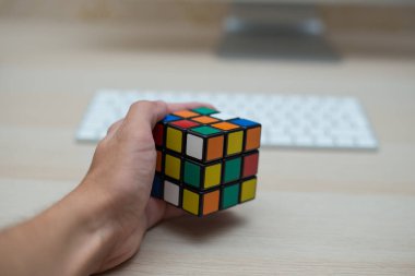 Elleri renkli bir yapboz. Rubik küpü 3 'er 3' er tahta bir masada yatıyor.