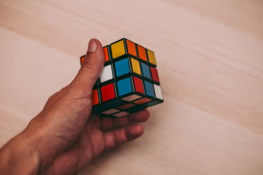 Elleri renkli bir yapboz. Rubik küpü 3 'er 3' er tahta bir masada yatıyor.
