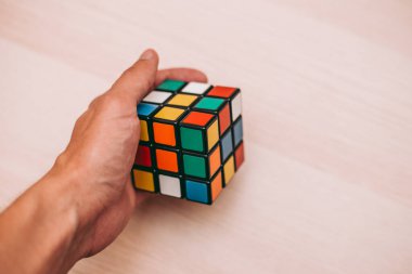 Elleri renkli bir yapboz. Rubik küpü 3 'er 3' er tahta bir masada yatıyor.