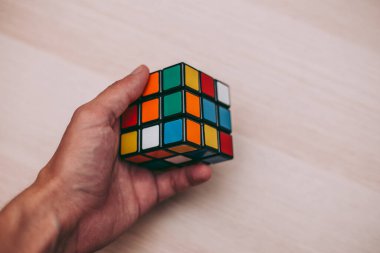 Elleri renkli bir yapboz. Rubik küpü 3 'er 3' er tahta bir masada yatıyor.