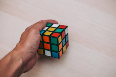Elleri renkli bir yapboz. Rubik küpü 3 'er 3' er tahta bir masada yatıyor.