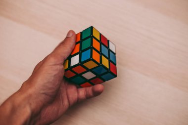Elleri renkli bir yapboz. Rubik küpü 3 'er 3' er tahta bir masada yatıyor.