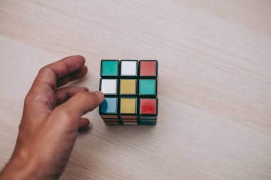 Elleri renkli bir yapboz. Rubik küpü 3 'er 3' er tahta bir masada yatıyor.