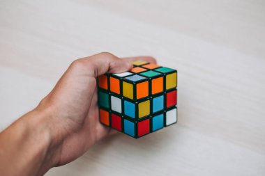 Elleri renkli bir yapboz. Rubik küpü 3 'er 3' er tahta bir masada yatıyor.