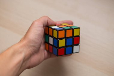 Elleri renkli bir yapboz. Rubik küpü 3 'er 3' er tahta bir masada yatıyor.