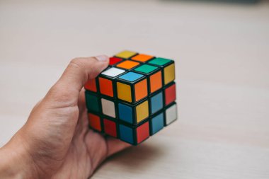 Elleri renkli bir yapboz. Rubik küpü 3 'er 3' er tahta bir masada yatıyor.