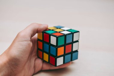 Elleri renkli bir yapboz. Rubik küpü 3 'er 3' er tahta bir masada yatıyor.