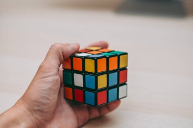 Elleri renkli bir yapboz. Rubik küpü 3 'er 3' er tahta bir masada yatıyor.