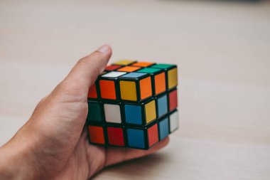 Elleri renkli bir yapboz. Rubik küpü 3 'er 3' er tahta bir masada yatıyor.