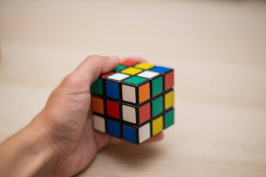 Elleri renkli bir yapboz. Rubik küpü 3 'er 3' er tahta bir masada yatıyor.
