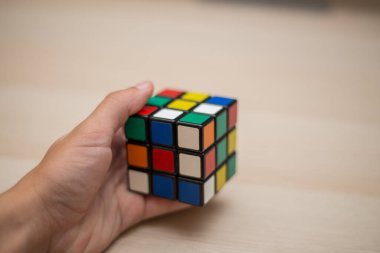 Elleri renkli bir yapboz. Rubik küpü 3 'er 3' er tahta bir masada yatıyor.