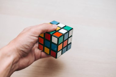 Elleri renkli bir yapboz. Rubik küpü 3 'er 3' er tahta bir masada yatıyor.