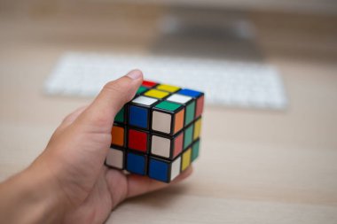 Elleri renkli bir yapboz. Rubik küpü 3 'er 3' er tahta bir masada yatıyor.