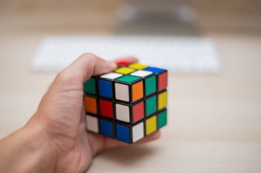 Elleri renkli bir yapboz. Rubik küpü 3 'er 3' er tahta bir masada yatıyor.