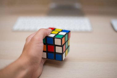 Elleri renkli bir yapboz. Rubik küpü 3 'er 3' er tahta bir masada yatıyor.