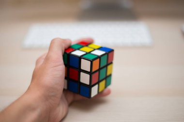 Elleri renkli bir yapboz. Rubik küpü 3 'er 3' er tahta bir masada yatıyor.