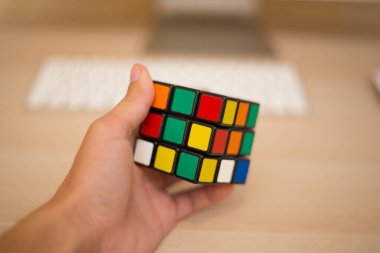 Elleri renkli bir yapboz. Rubik küpü 3 'er 3' er tahta bir masada yatıyor.