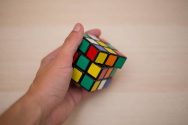 Elleri renkli bir yapboz. Rubik küpü 3 'er 3' er tahta bir masada yatıyor.