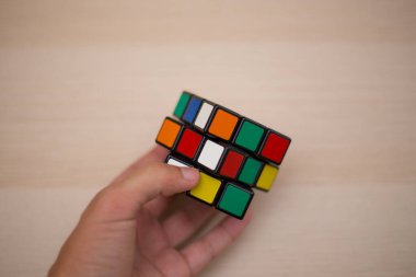 Elleri renkli bir yapboz. Rubik küpü 3 'er 3' er tahta bir masada yatıyor.