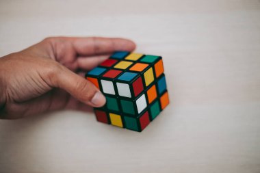 Elleri renkli bir yapboz. Rubik küpü 3 'er 3' er tahta bir masada yatıyor.
