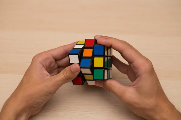 Elleri renkli bir yapboz. Rubik küpü 3 'er 3' er tahta bir masada yatıyor.