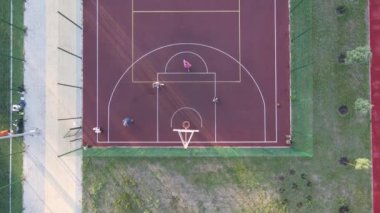 Sokakta basketbol oynayan genç bir adamın hava manzarası.