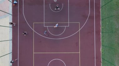 Sokakta basketbol oynayan genç bir adamın hava manzarası.