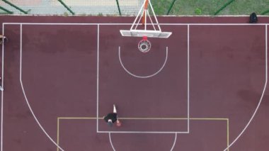 Sokakta basketbol oynayan genç bir adamın hava manzarası.