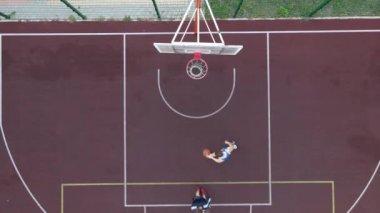 Sokakta basketbol oynayan genç bir adamın hava manzarası.