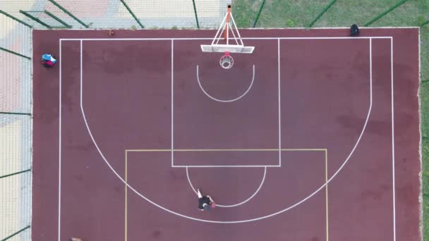 Letecký pohled na mladíka, který hraje basketbal na ulici — Stock video