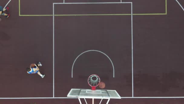 Вид с воздуха на молодого парня, играющего в баскетбол на улице — стоковое видео