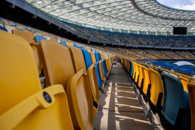 Sarı ve mavi bankları olan olimpiyat stadyumunda boş koltuklar.