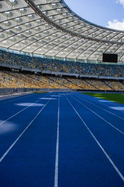 Olimpiyat stadyumundaki boş mavi koşu yolu boş tribünlerin arka planına karşı