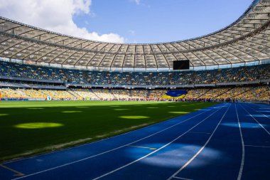 Olimpiyat stadyumundaki boş mavi koşu yolu boş tribünlerin arka planına karşı