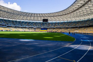 Olimpiyat stadyumundaki boş mavi koşu yolu boş tribünlerin arka planına karşı