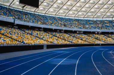Olimpiyat stadyumundaki boş mavi koşu yolu boş tribünlerin arka planına karşı
