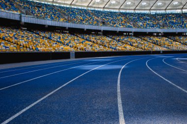 Olimpiyat stadyumundaki boş mavi koşu yolu boş tribünlerin arka planına karşı