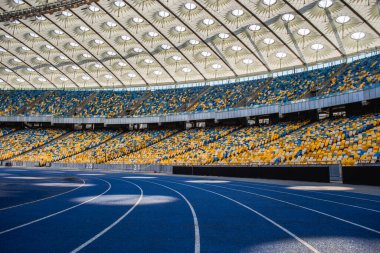 Olimpiyat stadyumundaki boş mavi koşu yolu boş tribünlerin arka planına karşı
