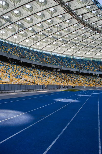 Empty blue running track at the olympic stadium against the background of empty stands