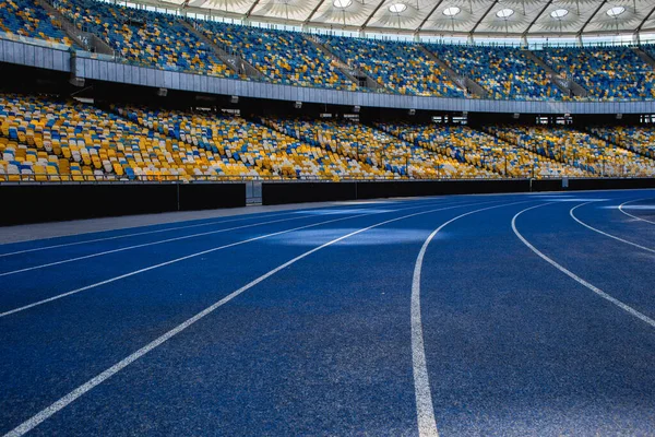 Olimpiyat stadyumundaki boş mavi koşu yolu boş tribünlerin arka planına karşı