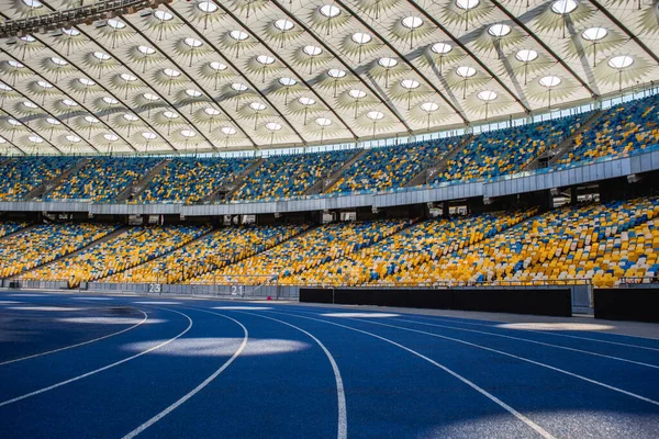 Olimpiyat stadyumundaki boş mavi koşu yolu boş tribünlerin arka planına karşı