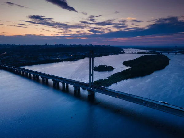 Vue aérienne depuis un drone sur un pont à haubans sur une rivière le soir — Photo