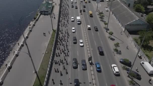 Vista aérea desde un avión no tripulado a un grupo de ciclistas en bicicleta en la carretera con tráfico — Vídeos de Stock