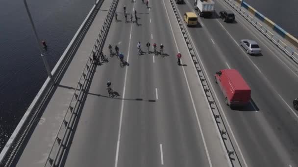 Vista aérea de um drone para um grupo de ciclistas em bicicletas passeio na estrada com tráfego — Vídeo de Stock