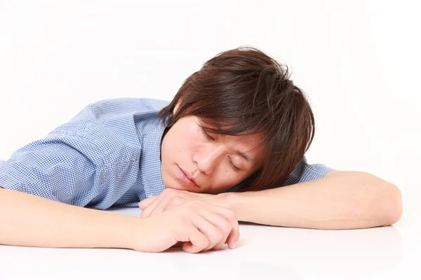 Молодой человек спит на столе — стоковое фото